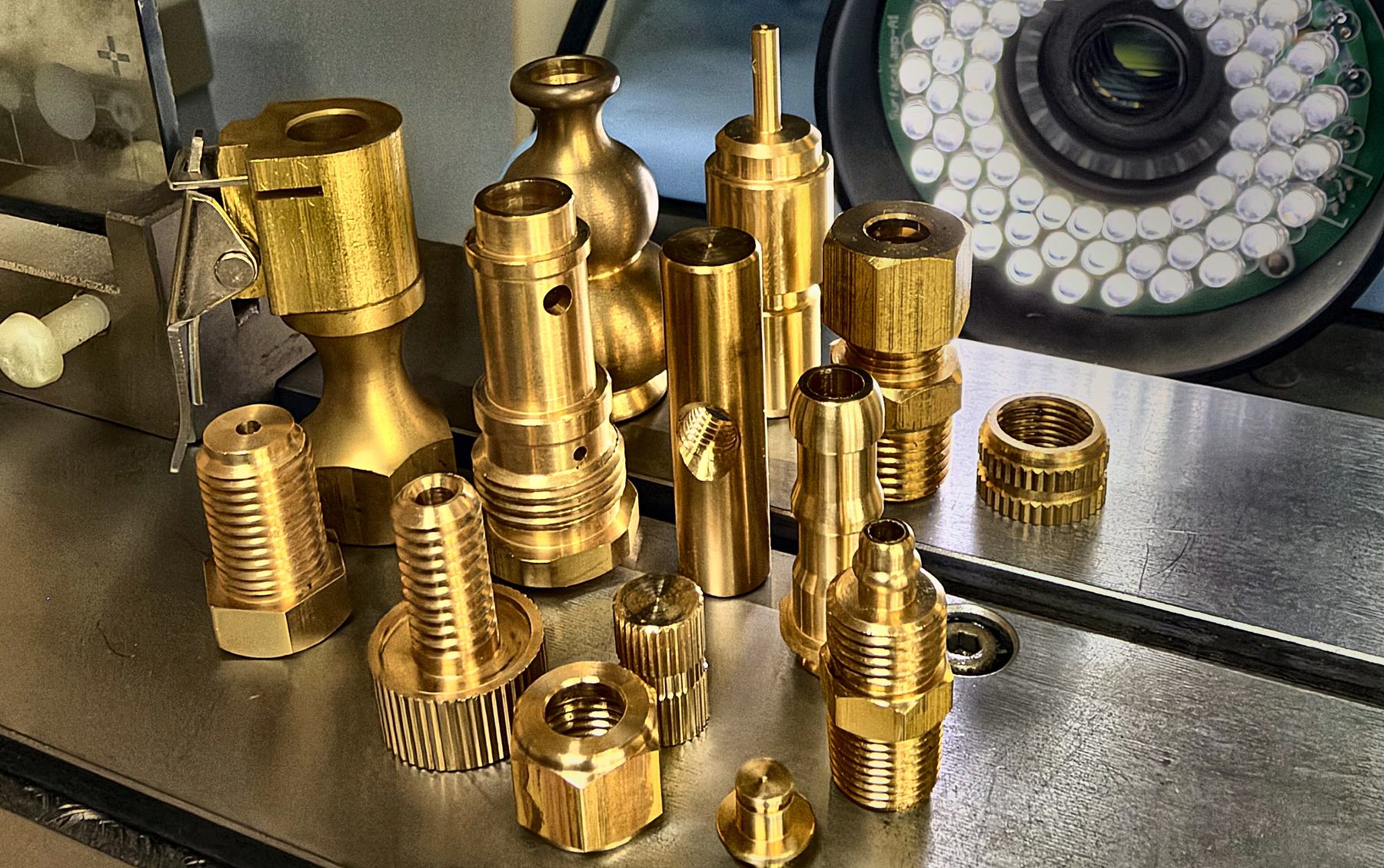 Turned brass fittings and valve components on a machined steel surface